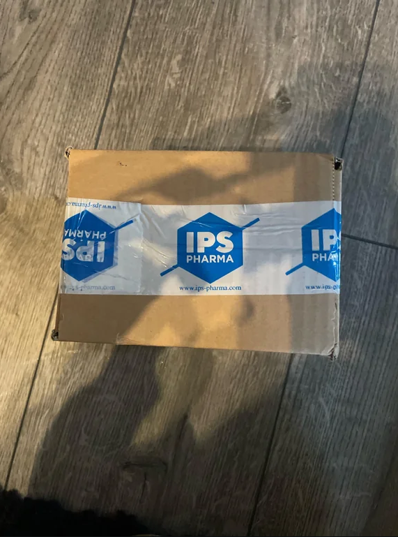 Cardboard box sealed with IPS Pharma branded tape, showing company name and website URL.