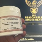 Box of IPS JFA T20 Jet Fuel Apricot medical cannabis shown in front of The Reasonable Adjustment website on a laptop screen.