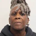 Custody photograph of Janice Nix, an older woman with grey locs, wearing a dark hooded top, looking directly at the camera.
