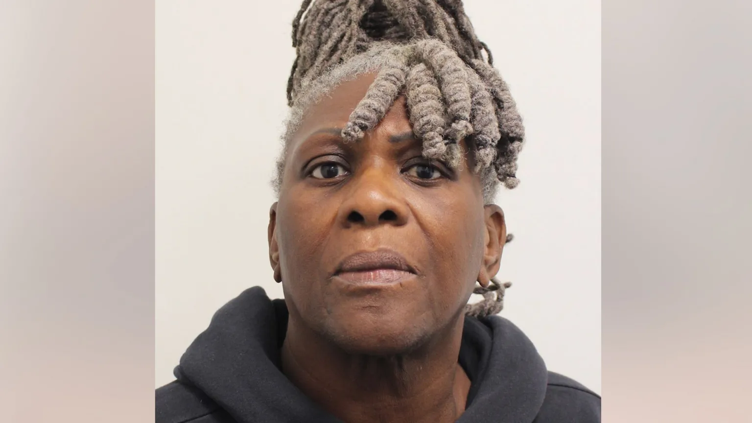 Custody photograph of Janice Nix, an older woman with grey locs, wearing a dark hooded top, looking directly at the camera.