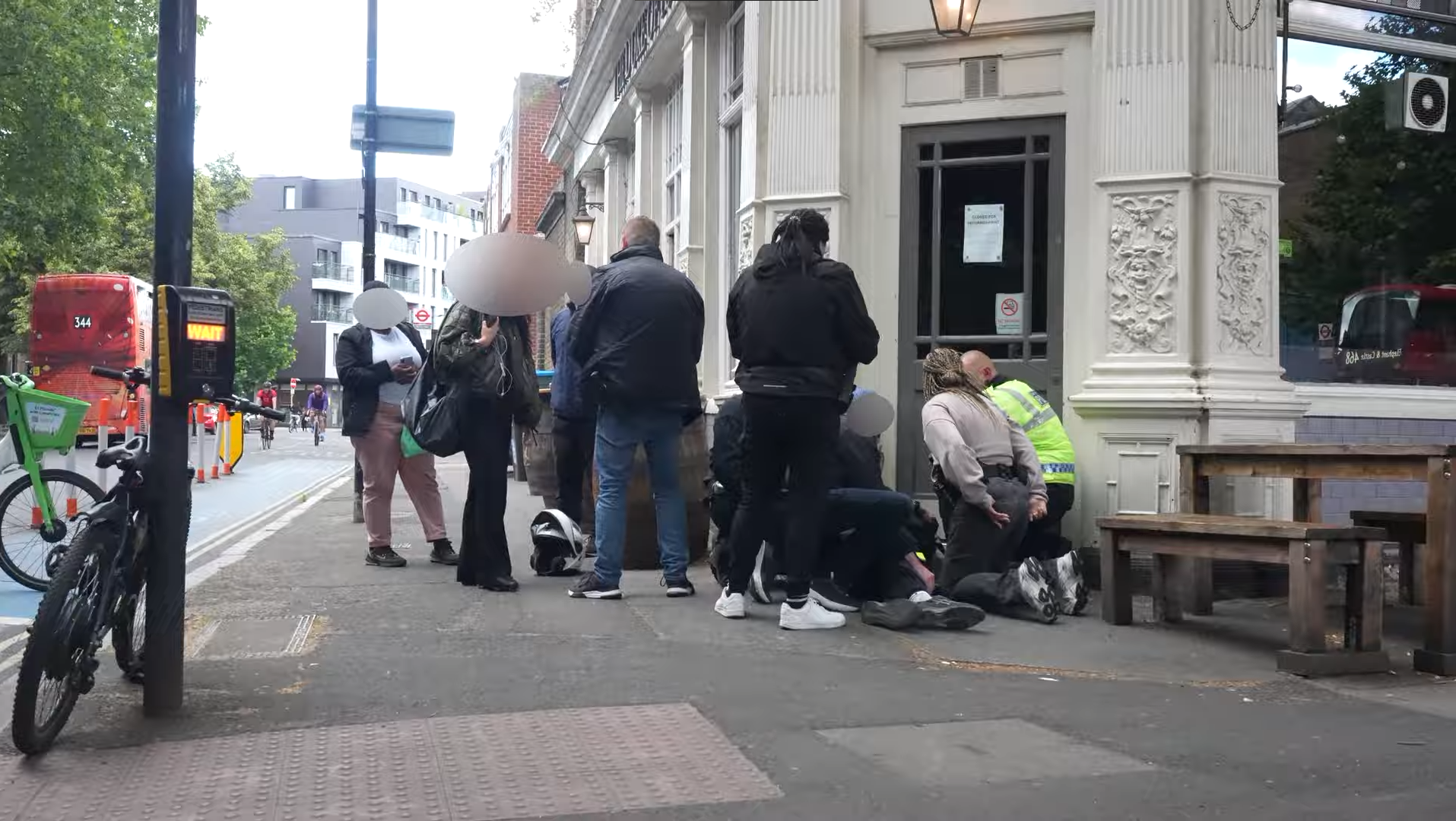 Metropolitan Police officers surrounding a young man restrained on a London pavement as bystanders watch
