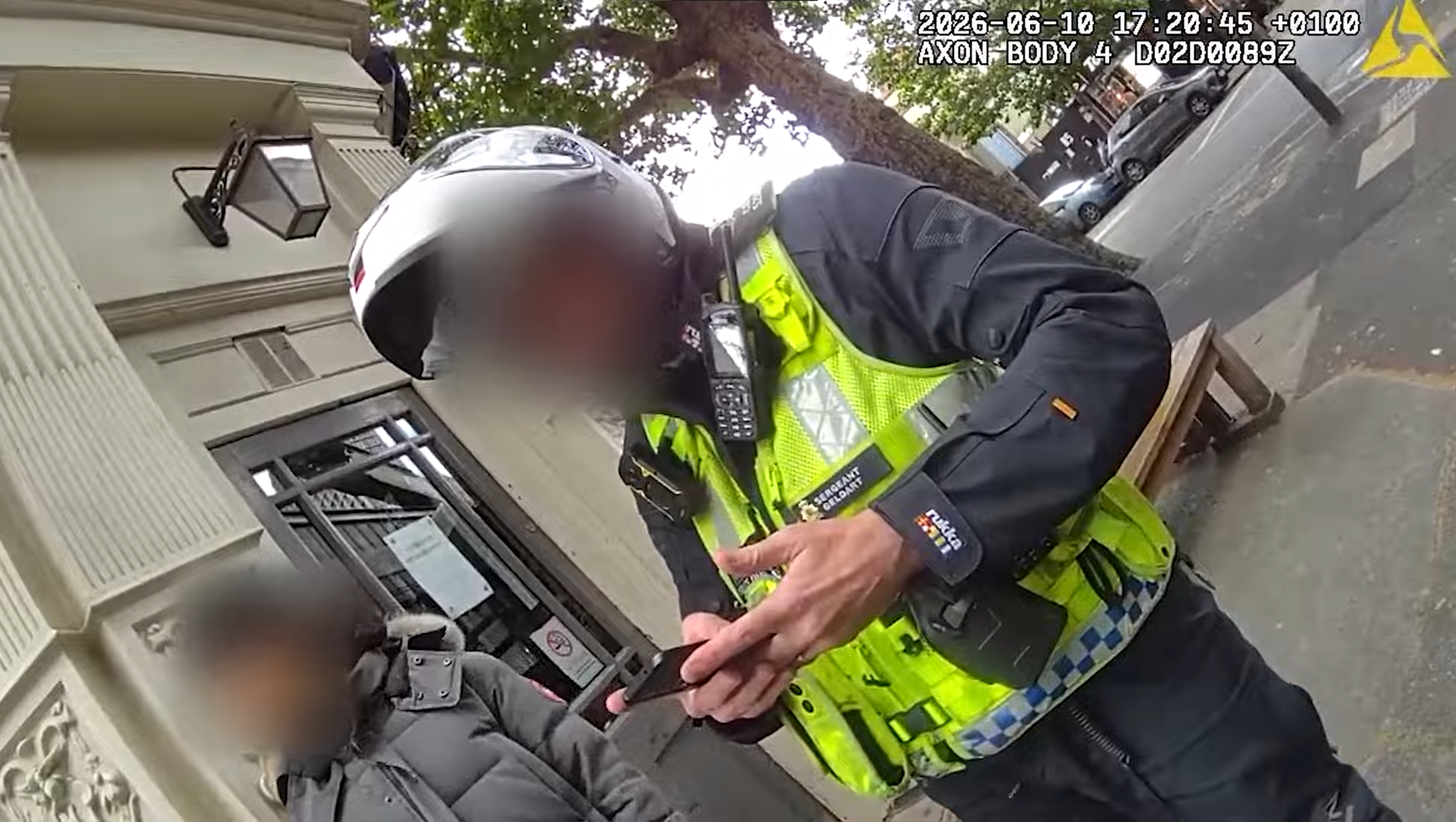 Met sergeant in a motorcycle helmet and high-visibility vest leaning towards a much smaller person during a London stop